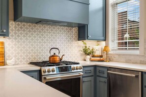 A modern kitchen with a gas stove, oven, and built-in cabinets. - The Bentonville Brownstone | Luxury Stay Downtown (Bentonville)