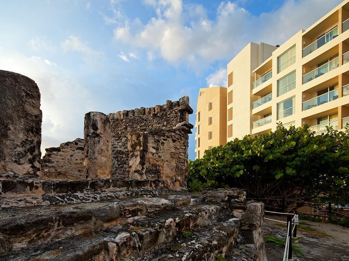 Ancient ruins with a modern building in the background.
