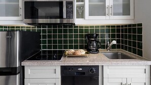 Una cucina con microonde, macchina per il caffè e scolapiatti con prodotti da forno.