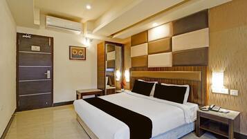 Quarto de hotel com uma cama grande, mesa de cabeceira, espelho e porta com uma placa.