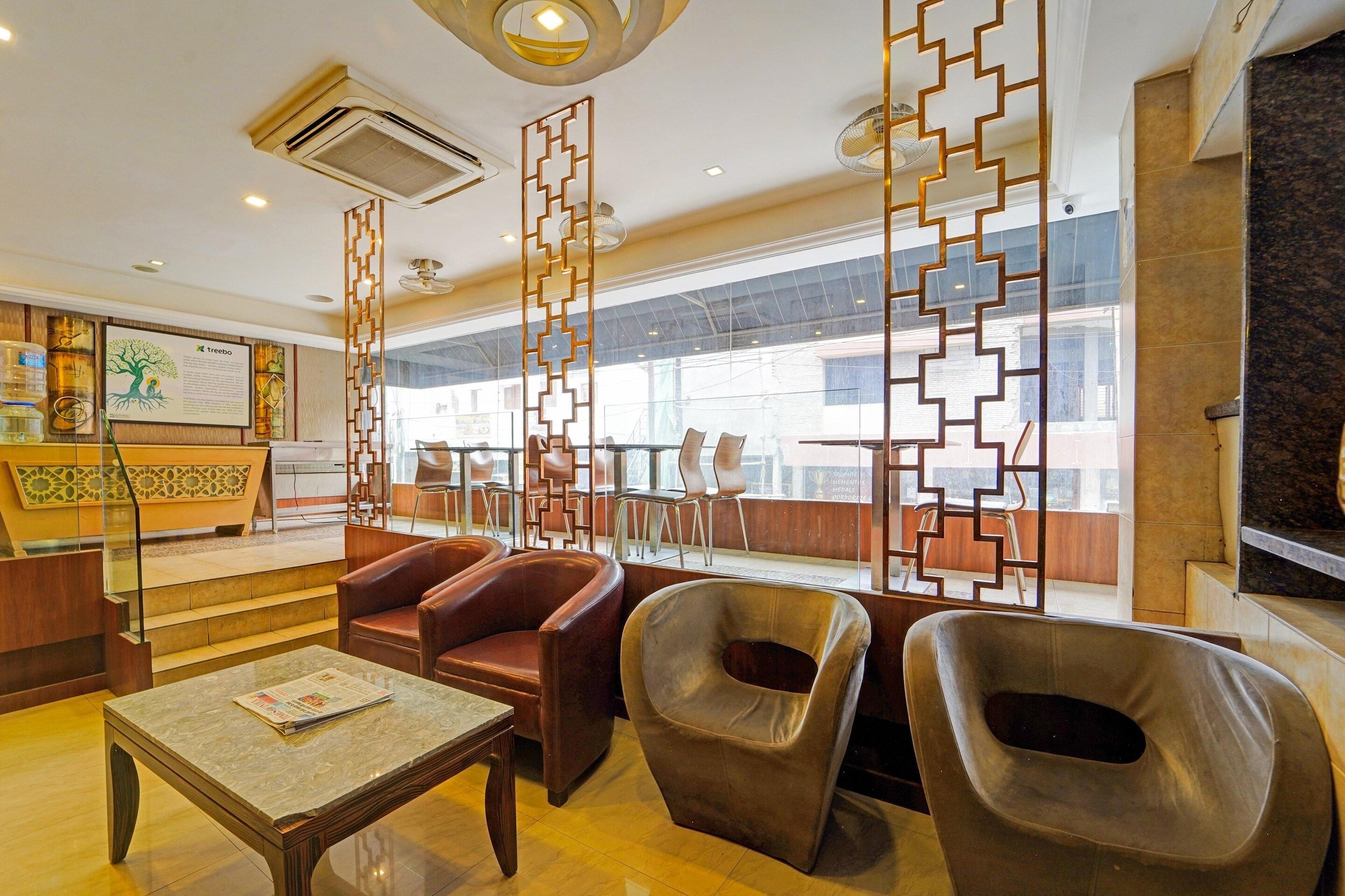 Un vestíbulo de hotel con mostrador de recepción, asientos de cuero, una mesa de mármol y paneles decorativos.