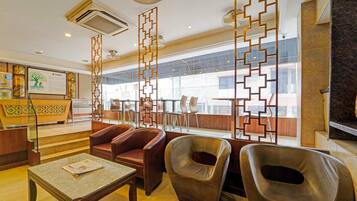 Un vestíbulo de hotel con mostrador de recepción, asientos de cuero, una mesa de mármol y paneles decorativos.