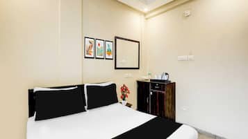 Quarto de hotel com uma cama grande, uma mesinha com uma chaleira e um armário.