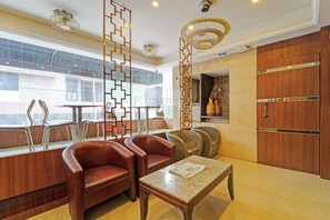 A hotel lobby with leather chairs, a coffee table, a decorative wall, and a wooden door. - Deluxe Room RK Residency (Coimbatore)
