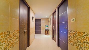 A hotel corridor with two doors, a reception desk, and a small table with a chair.
