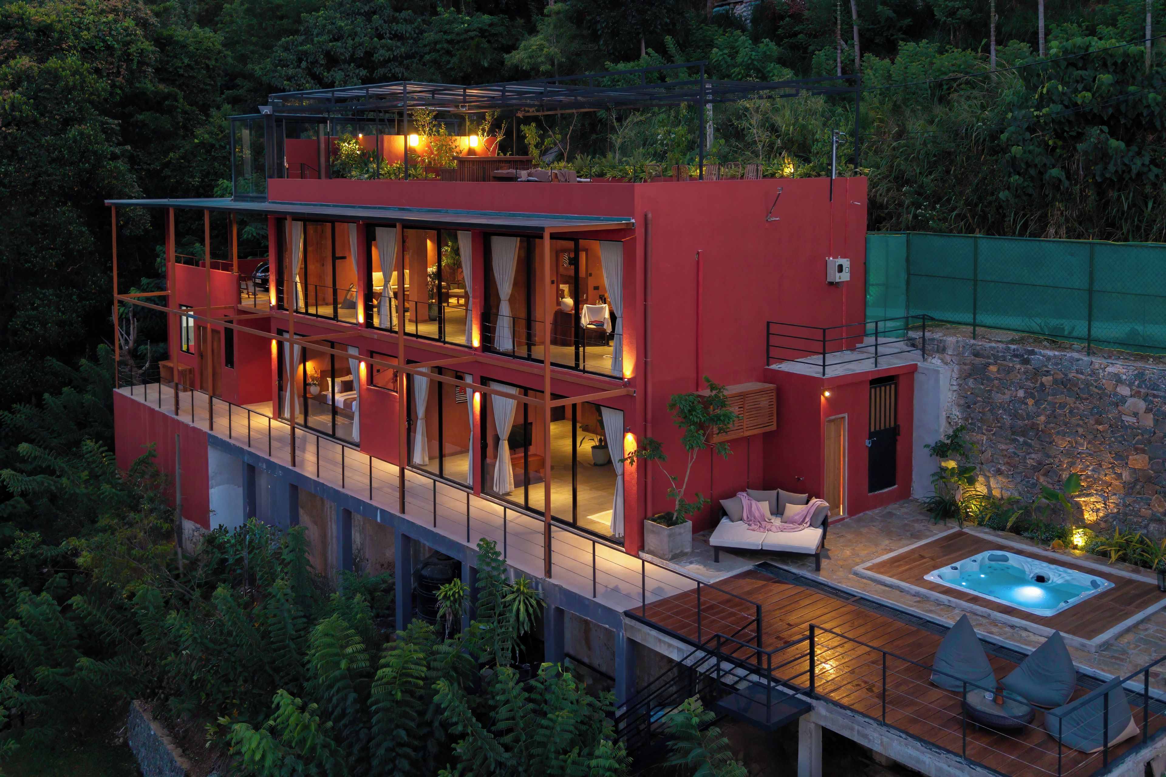 A modern two-story house with a glass facade, a rooftop garden, and a hot tub on the ground floor.