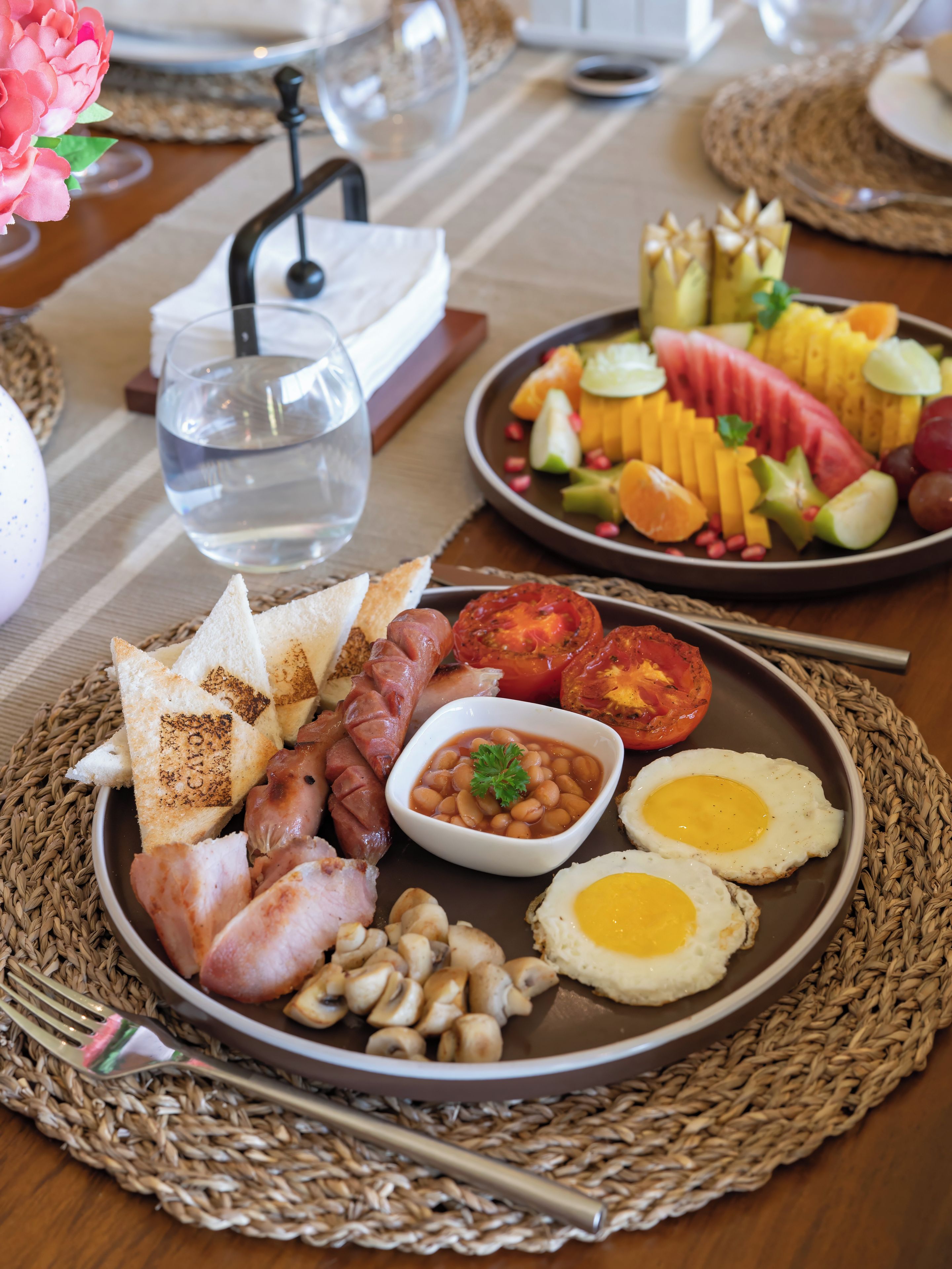 Ein reichhaltiges Frühstücksbuffet mit Toast, Würstchen, Bohnen, Eiern sowie verschiedenen Früchten und Gemüsesorten.