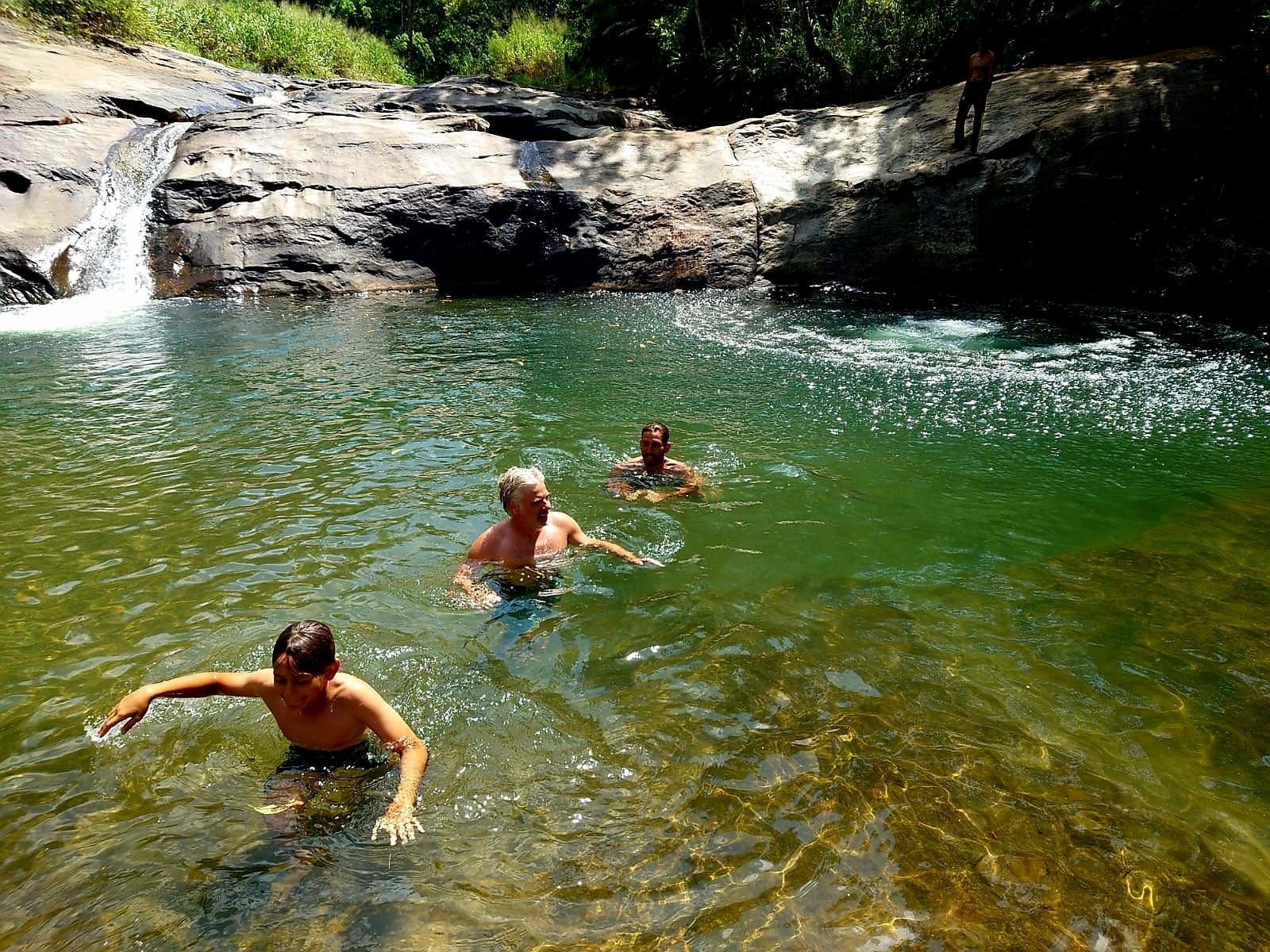 A natural water body with clear water, surrounded by rocks and greenery.