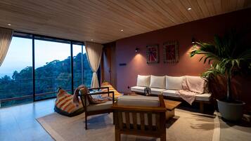 Una sala de estar moderna con un ventanal grande, un sofá, una mesa de centro de madera y una planta en maceta.
