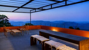 Un espace extérieur aménagé avec des sièges, offrant une vue sur les montagnes au crépuscule.
