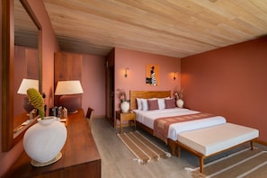 A hotel room with a wooden ceiling, a bed with a headboard, a bedside table with a lamp, a large vase, and a wall-mounted artwork.