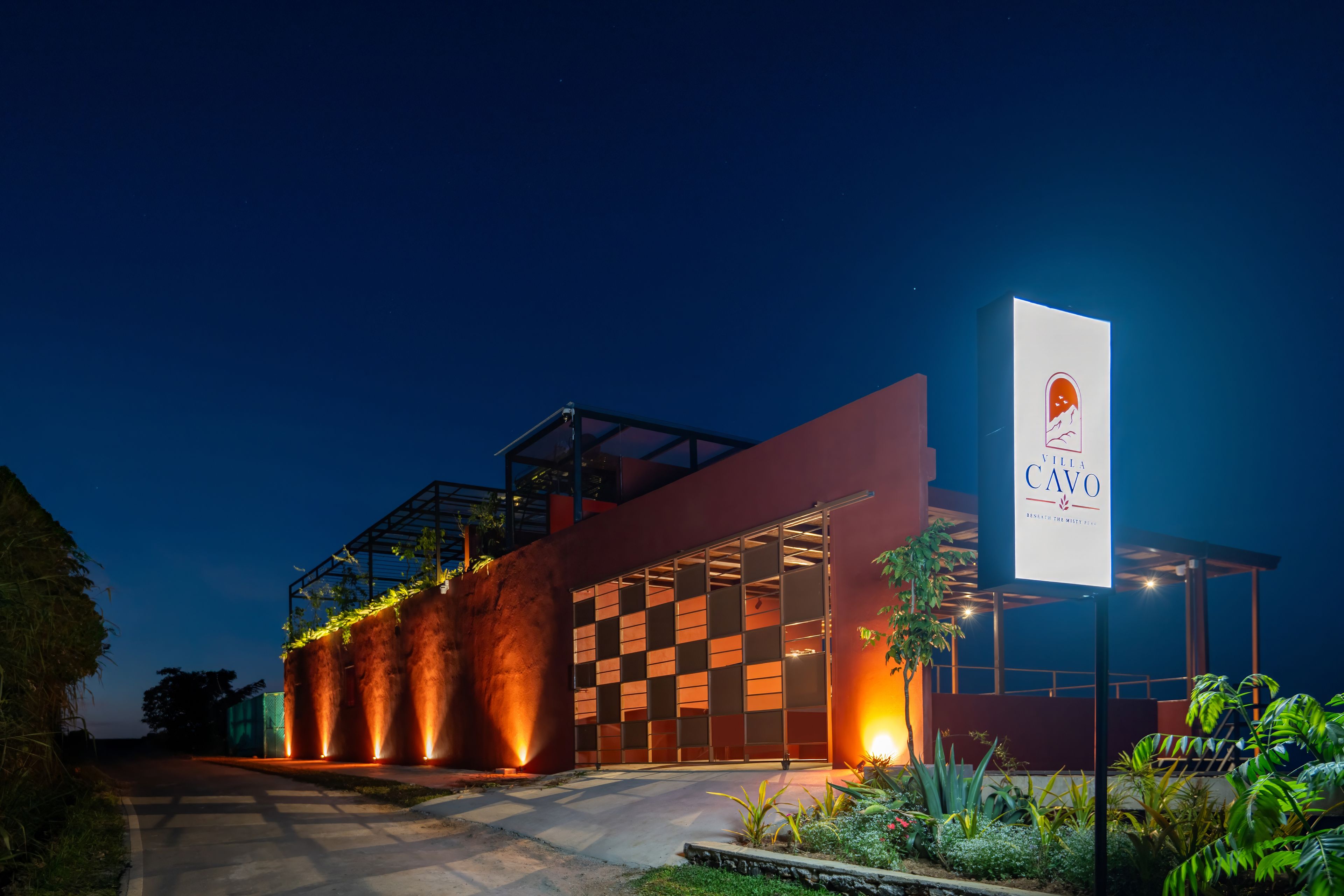 A modern building with a large illuminated sign, a covered outdoor area, and a pathway leading to the entrance.