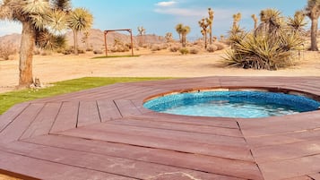 A wooden deck surrounding a swimming pool with desert vegetation in the background.