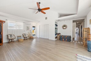 Une pièce spacieuse dotée d’un ventilateur de plafond, de planchers en bois et d’une grande armoire.