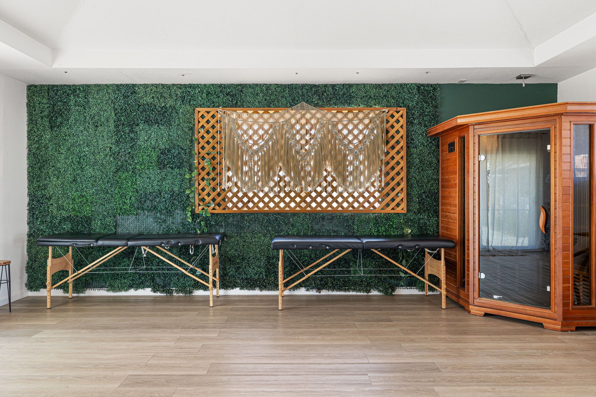 A room with two massage tables, a wooden cabinet, and a green wall with a lattice design.