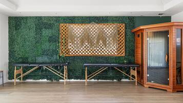 A room with two massage tables, a wooden cabinet, and a green wall with a lattice design.