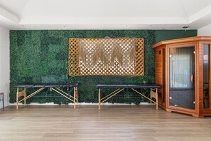Une pièce comprenant deux tables de massage, un meuble en bois et un mur vert orné d’un motif en treillis.