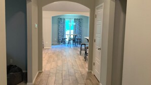 A hallway with wooden flooring, a dining area with chairs and a table, and a door on the right. -  New, clean, spacious and cozy! Pet friendly!  (Broken Arrow)