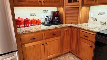 A kitchen with wooden cabinets, a granite countertop, and a stainless steel refrigerator.
