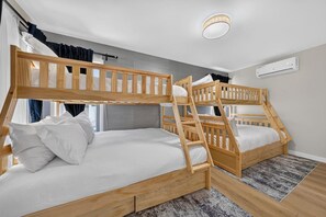 A bunk bed room with a ladder, white bedding, a gray rug, and an air conditioning unit. - Modern Coastal Luxury, Ocean views, garage parking (San Diego)
