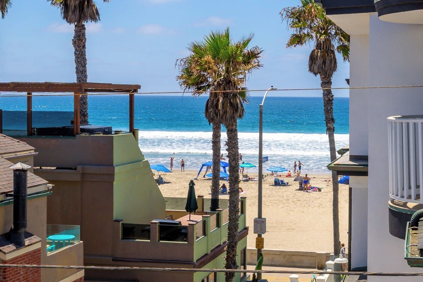 A beach view with palm trees, a sandy beach, and a clear blue ocean.
