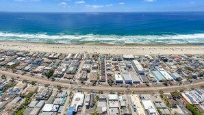 Vista aérea de una zona costera con playa y aparcamiento lleno de vehículos.