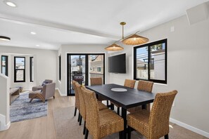 A modern dining area with a dark table, woven chairs, and a ceiling light fixture. - Modern Coastal Luxury, Ocean views, garage parking (San Diego)