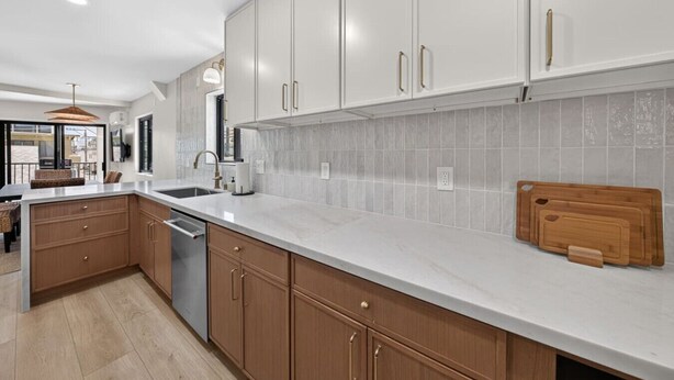 Cocina moderna con armarios blancos, encimera de mármol y tabla de cortar de madera.