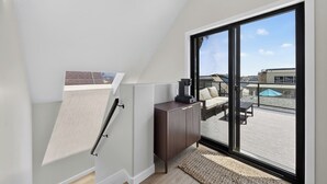 Un dormitorio tipo loft moderno con un gran ventanal corredero que da a una terraza exterior.