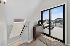 Ein modernes Schlafzimmer im Loft-Stil mit einem großen Schiebeglasfenster, das auf eine Terrassenauslauf führt.