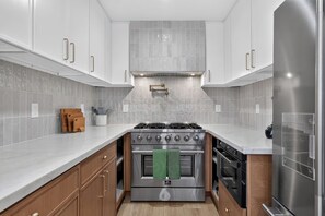 A modern kitchen with white cabinets, a stainless steel stove, and a built-in oven. - Modern Coastal Luxury, Ocean views, garage parking (San Diego)