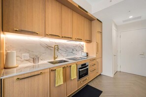 A modern kitchen with wooden cabinets, a marble countertop, a sink, a stove, and a toaster. - Miami 1BR Apartment with Pool Ideal for 3 Guests (Miami)