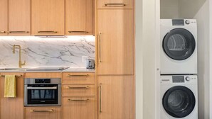 Eine Küche mit Holzschränken, einer Marmorarbeitsplatte, einem Spülbecken, einem Toaster, einem Backofen und einer Waschmaschine.