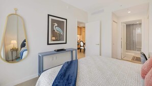 Ein Schlafzimmer mit einem Bett, einem Schminktisch, einem Spiegel und einem gerahmten Bild an der Wand.
