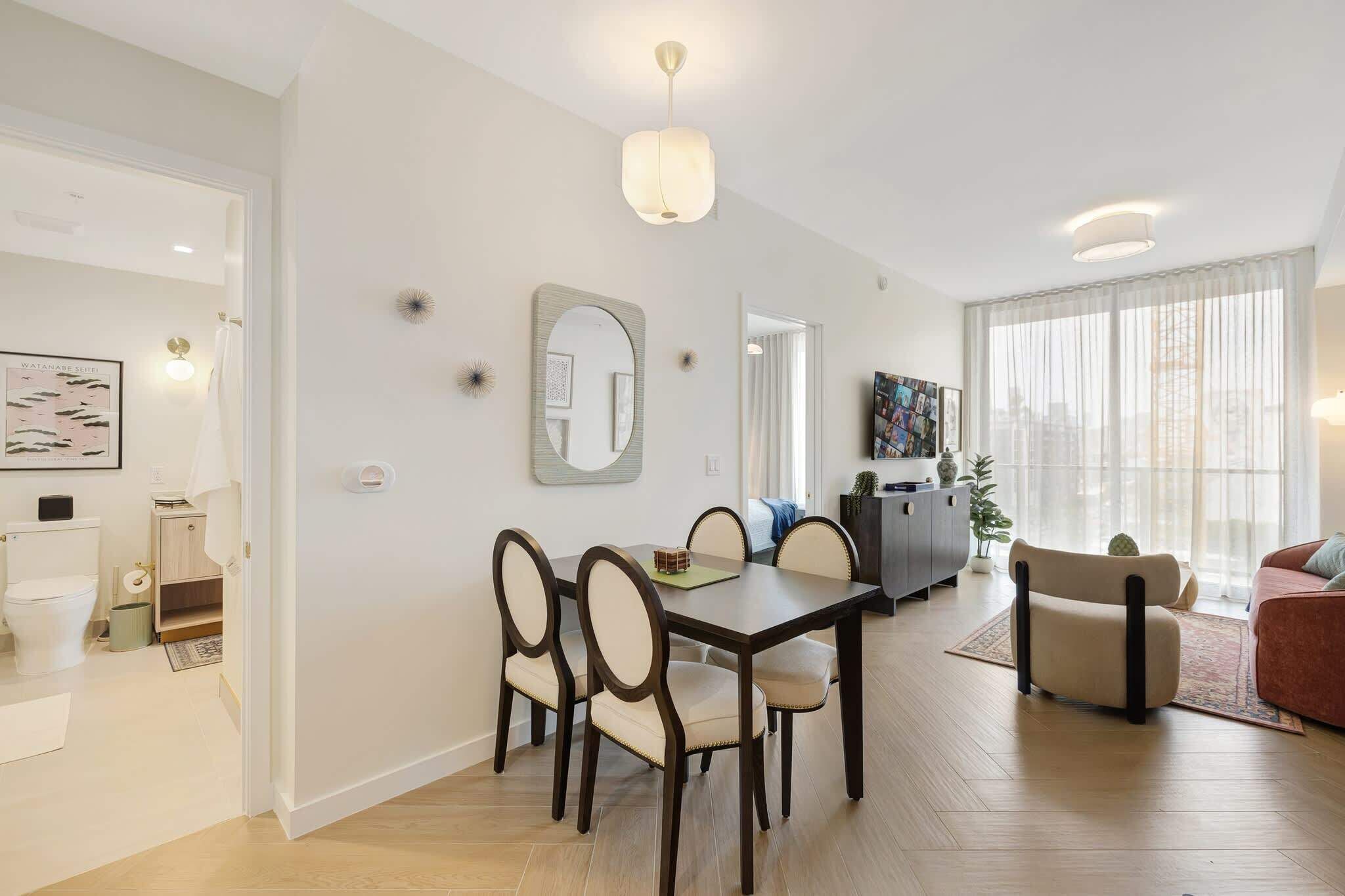 Un salon moderne comprenant un coin repas, un canapé, une table basse et une grande fenêtre avec des rideaux.