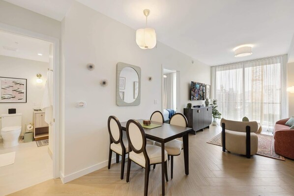 Un salon moderne comprenant un coin repas, un canapé, une table basse et une grande fenêtre avec des rideaux.
