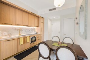 A modern kitchen with wooden cabinets, a marble countertop, and a built-in oven. - Miami 1BR Apartment with Pool Ideal for 3 Guests (Miami)