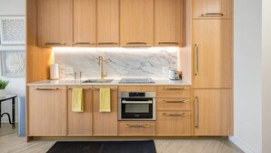Eine moderne Küche mit Holzschränken, einem Bosch-Ofen und einer Marmorarbeitsplatte.