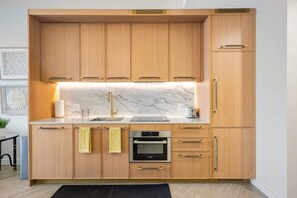 Eine moderne Küche mit Holzschränken, einem Bosch-Ofen und einer Marmorarbeitsplatte.