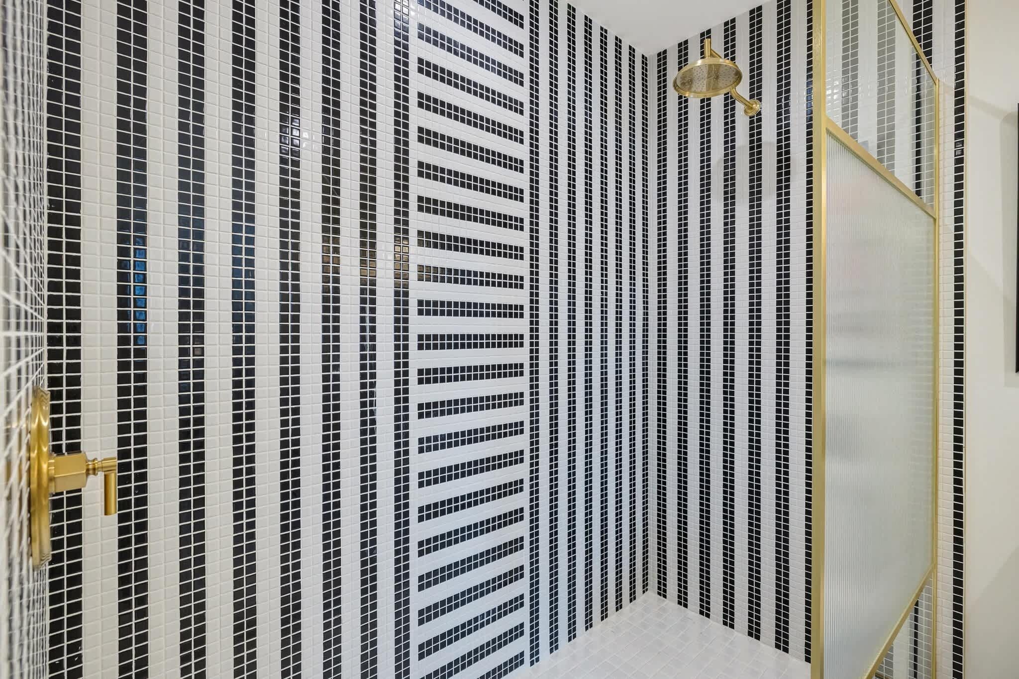 Une salle de bain avec un mur recouvert de carreaux présentant un motif à rayures noires et blanches.