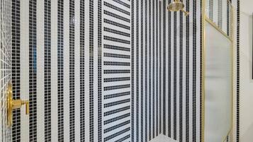 Une salle de bain avec un mur recouvert de carreaux présentant un motif à rayures noires et blanches.