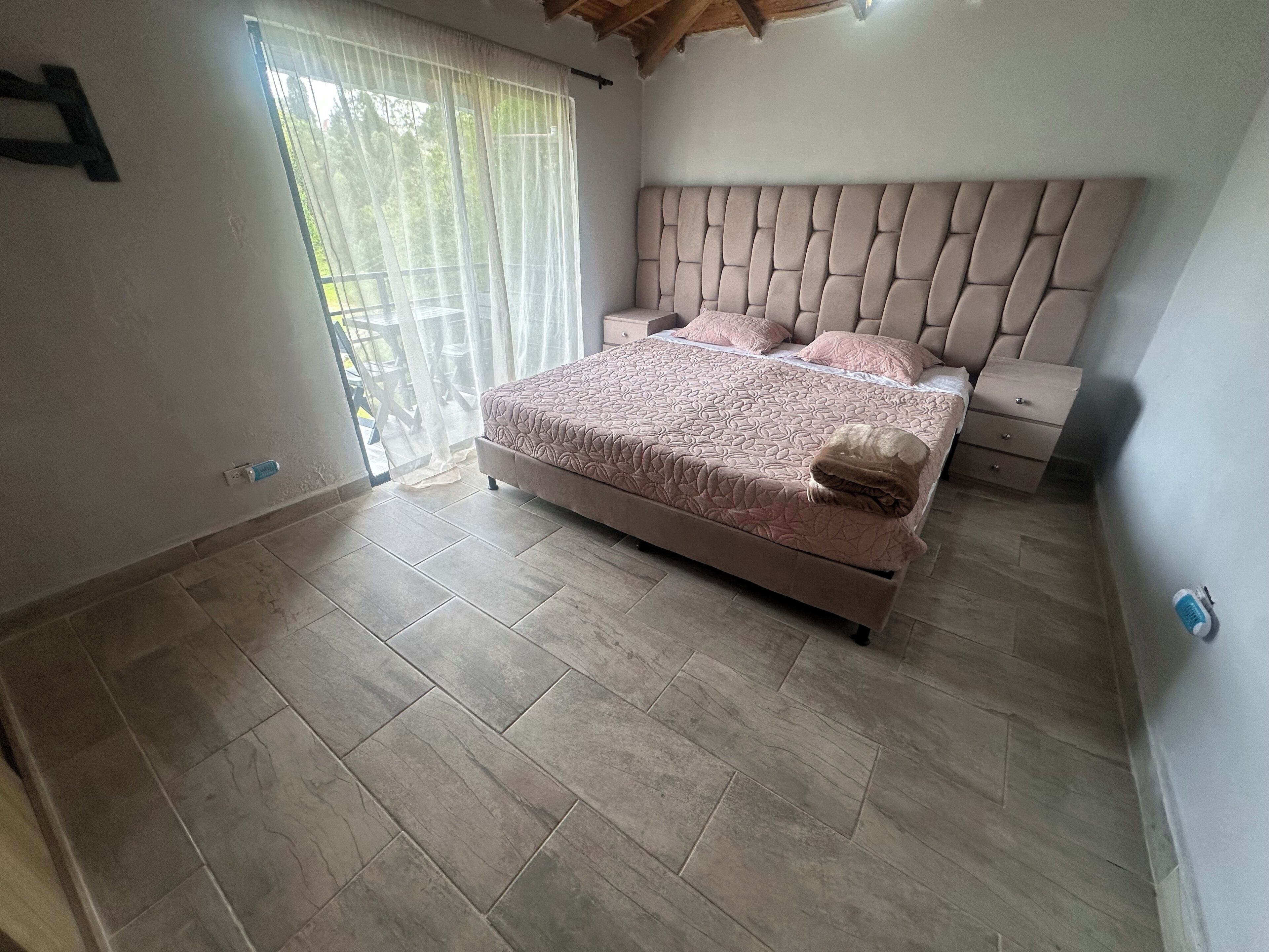 Een slaapkamer met een bed, nachtkastjes en een raam met gordijnen.