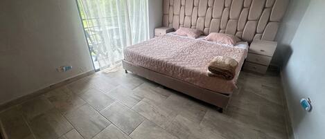 A bedroom with a bed, bedside tables, and a window with curtains.