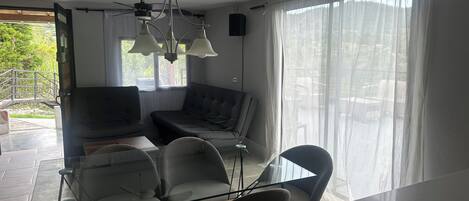 Una sala de estar moderna con una mesa de comedor de vidrio, dos sofás y un ventilador de techo.