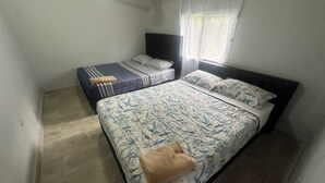 A bedroom with two beds, one with a floral bedspread and the other with striped bedding.