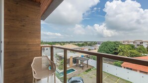 Uma varanda com vista para uma área residencial, uma piscina e um carro estacionado abaixo.