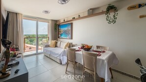 Sala de estar moderna com área de refeições, janelas amplas e vista para a paisagem urbana.