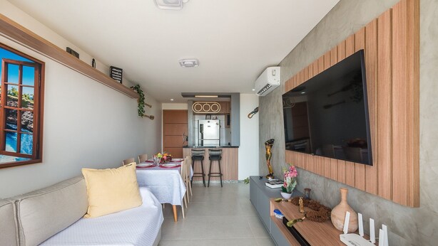 Um espaço compacto com área de jantar, cozinha compacta e TV fixada na parede.