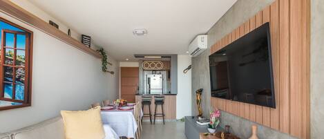 A compact living space with a dining area, kitchenette, and a TV mounted on the wall.