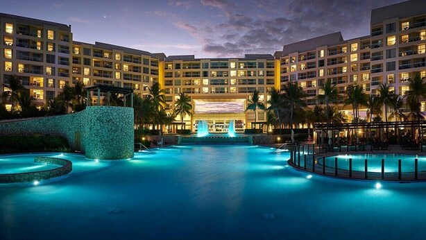 Un hotel con varias plantas, piscina y zona de bar.
